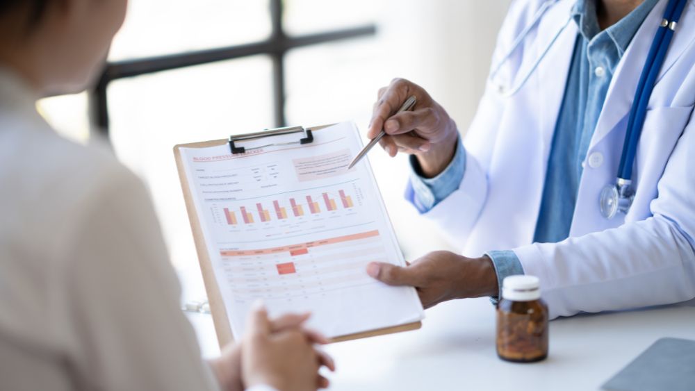 Doctor explaining blood test report results to a patient during a medical consultation.